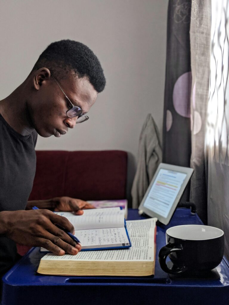 pexels-photo-2325729-2325729 Young man deeply immersed in reading and studying with books and tablet.